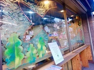 『ブック&カフェスタンドShinjo Gekijo』の店舗ガラス窓にキットパスで絵本の世界を表現した