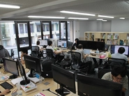 本社の風景（福岡市）。大画面デュアルモニター、広いデスク、高性能PCを完備しています。