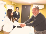 三重県の中小企業のイノベーションプロジェクトに飛び込む学生と社長の微笑ましい写真。と、その後ろで、混ざりたいけど混ざり切れなかった、ちょっとお茶目な代表の中村。