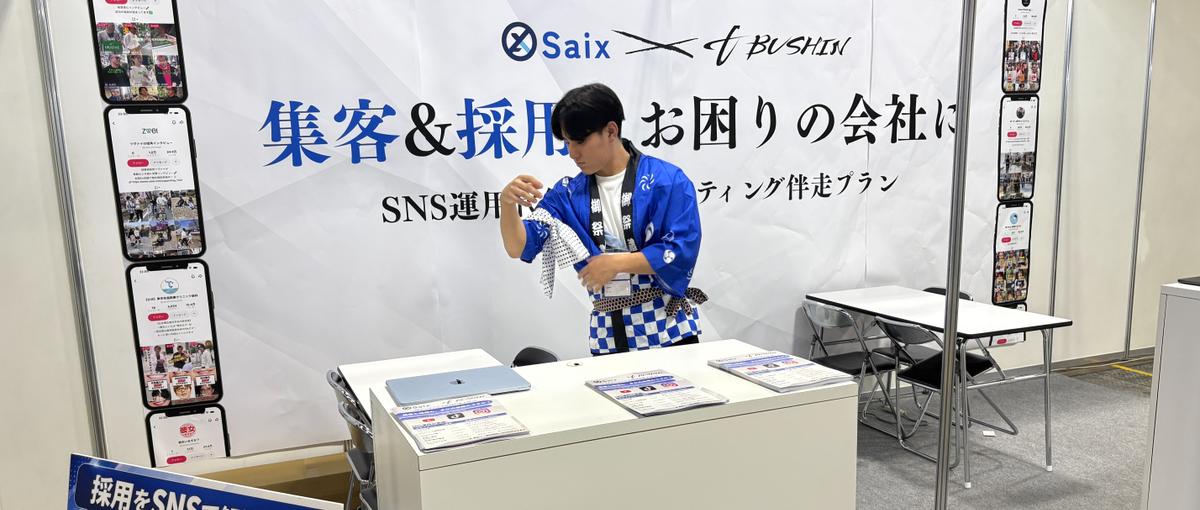 AI展示会のブースで、来場した経営者に声をかける営業スタッフ